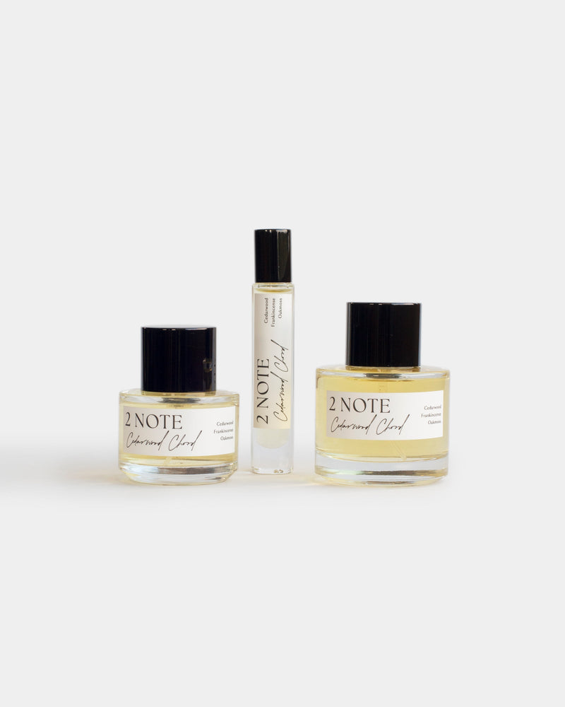 Cedarwood Chord botanical fragrance in three sizes — small and large spray bottles and a roller, pale yellow oil through clear glass