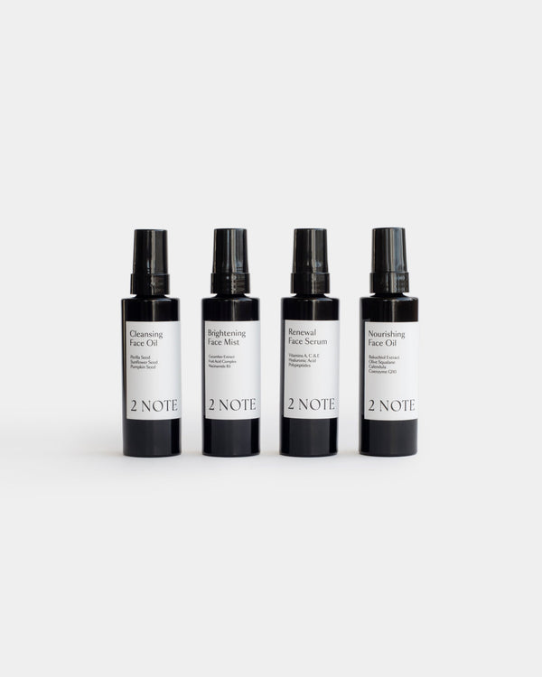 The Face Ritual Set — Cleansing Face Oil, Brightening Face Mist, Renewal Face Serum, and Nourishing Face Oil matte black bottles side by side on light gray, full botanical skincare face routine