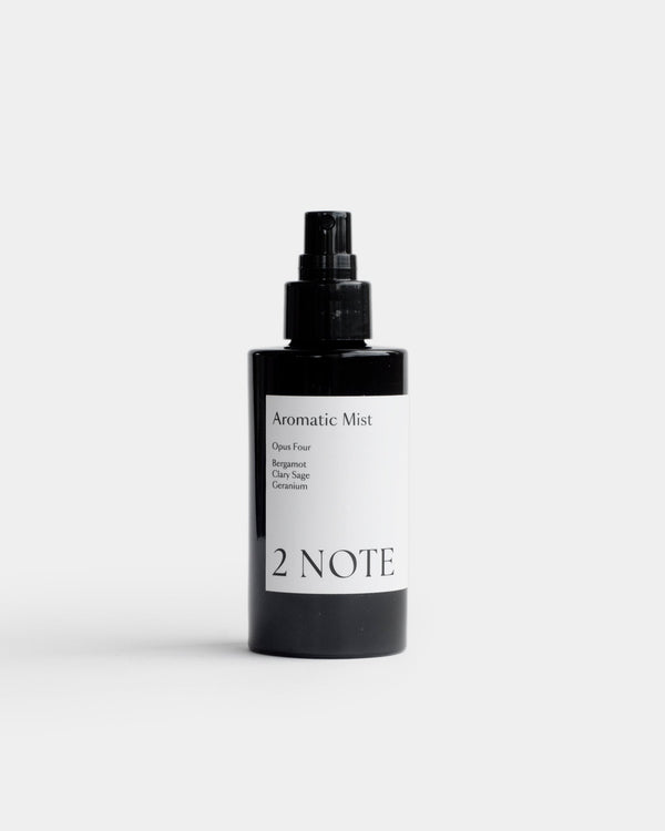 Aromatic Mist in matte black fine-mist spray bottle — botanical fragrance room and body mist with Bergamot, Clary Sage, and Geranium, front view on light gray