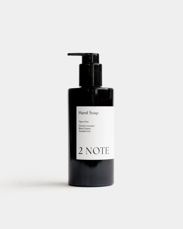 Hand Soap in tall matte black pump bottle — botanical skincare liquid hand wash with French Lavender, Black Pepper, and Sandalwood, front view on light gray