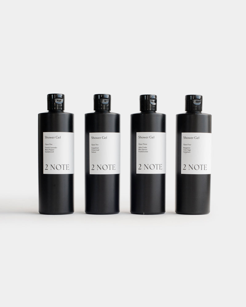 Four Shower Gel matte black flip-top bottles side by side — all scent variants of this botanical skincare body wash, light gray background