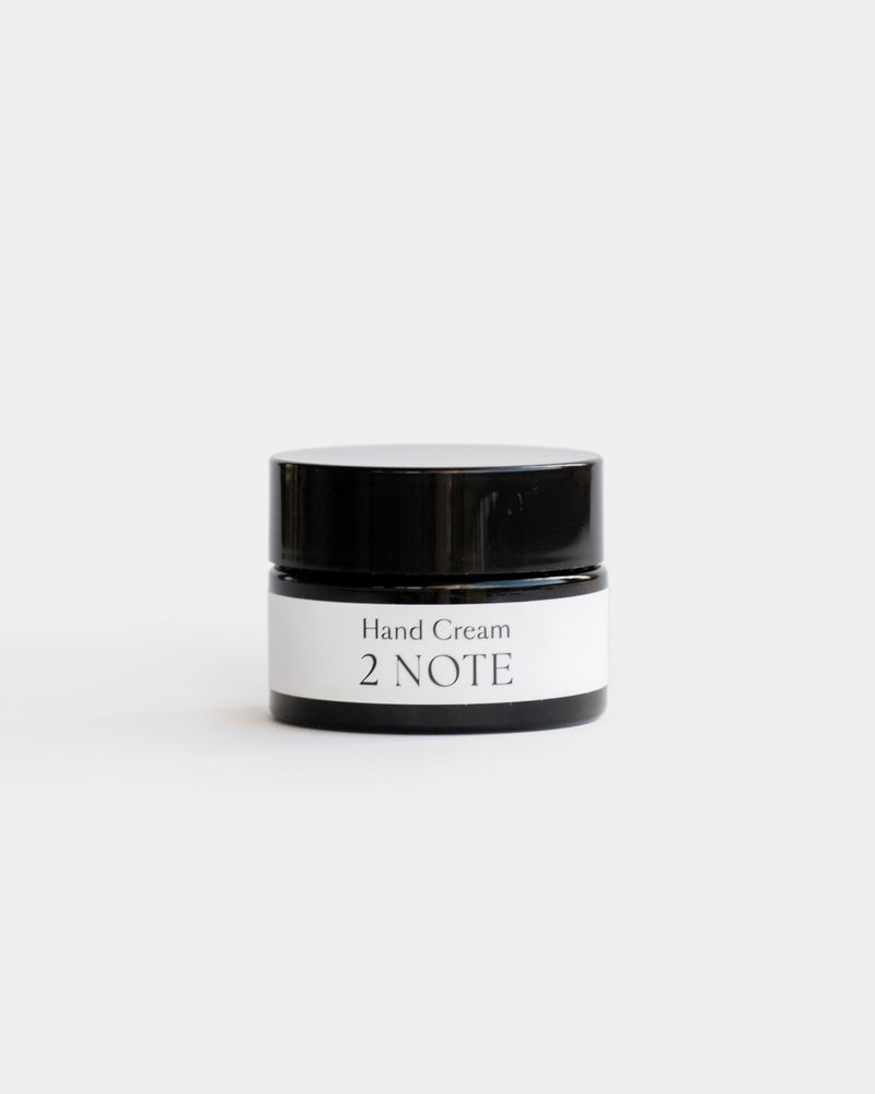 Hand Cream in small matte black glass jar — botanical natural skincare hand cream, front view on light gray