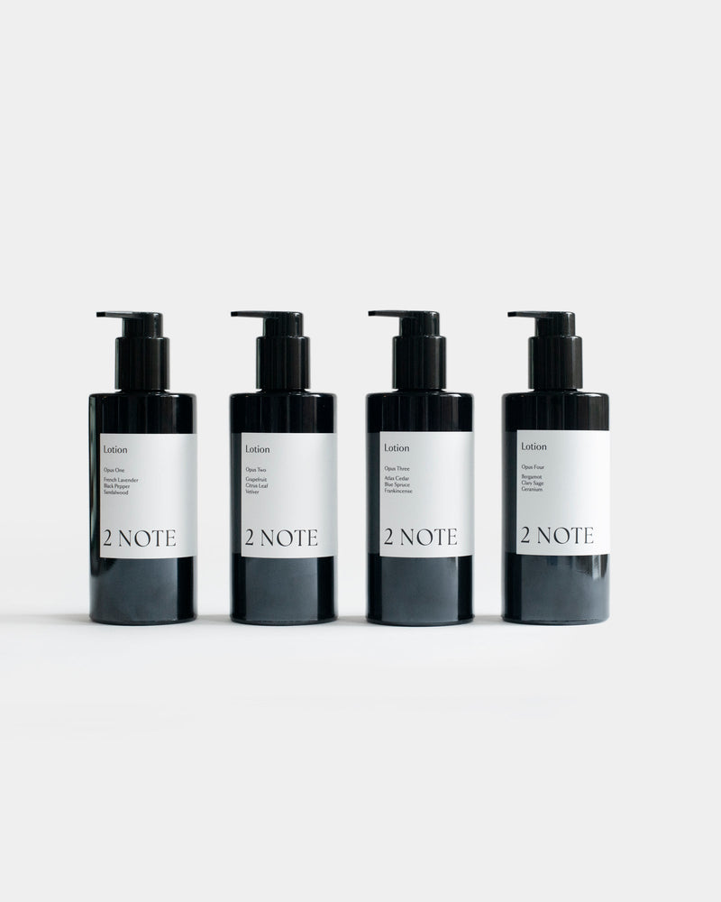 Four Lotion matte black pump bottles side by side — all scent variants of this botanical skincare body lotion, light gray background