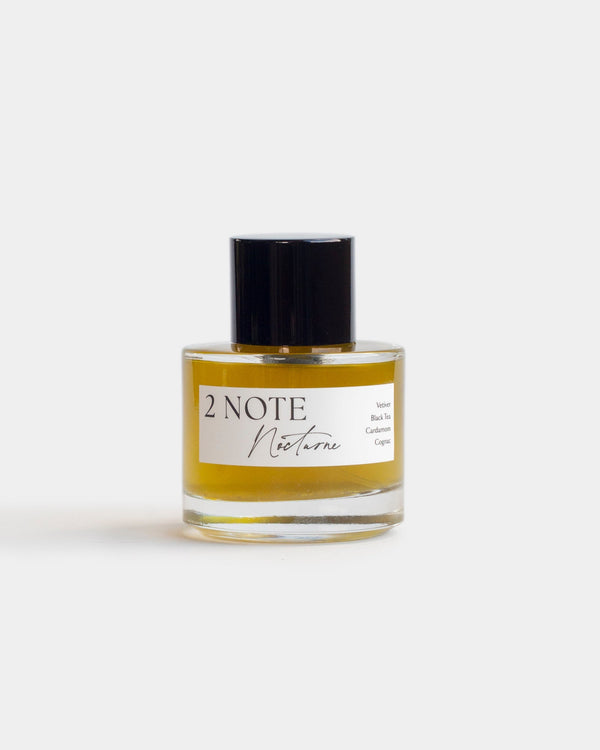 Nocturne in clear glass spray bottle — botanical natural fragrance, rich golden amber oil, front view on white