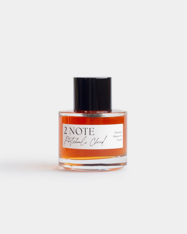 Patchouli Chord in clear glass spray bottle — single-note botanical fragrance, deep terracotta oil, front view on white