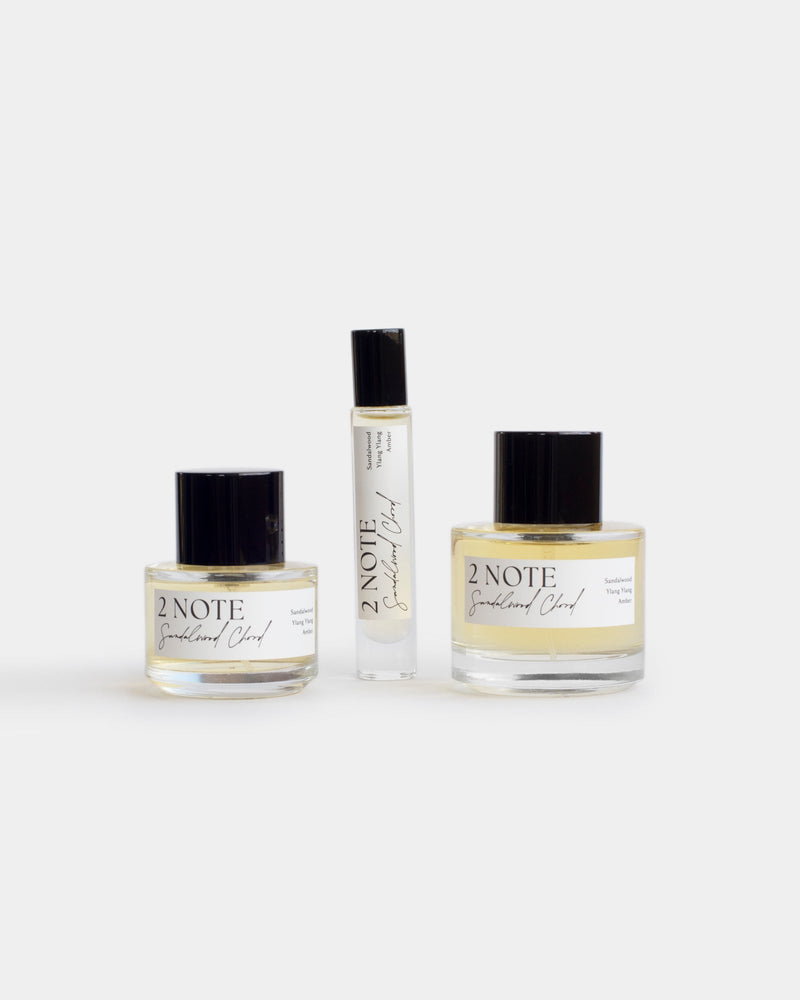 Sandalwood Chord botanical fragrance in three sizes — small and large spray bottles and a roller, pale straw oil through clear glass
