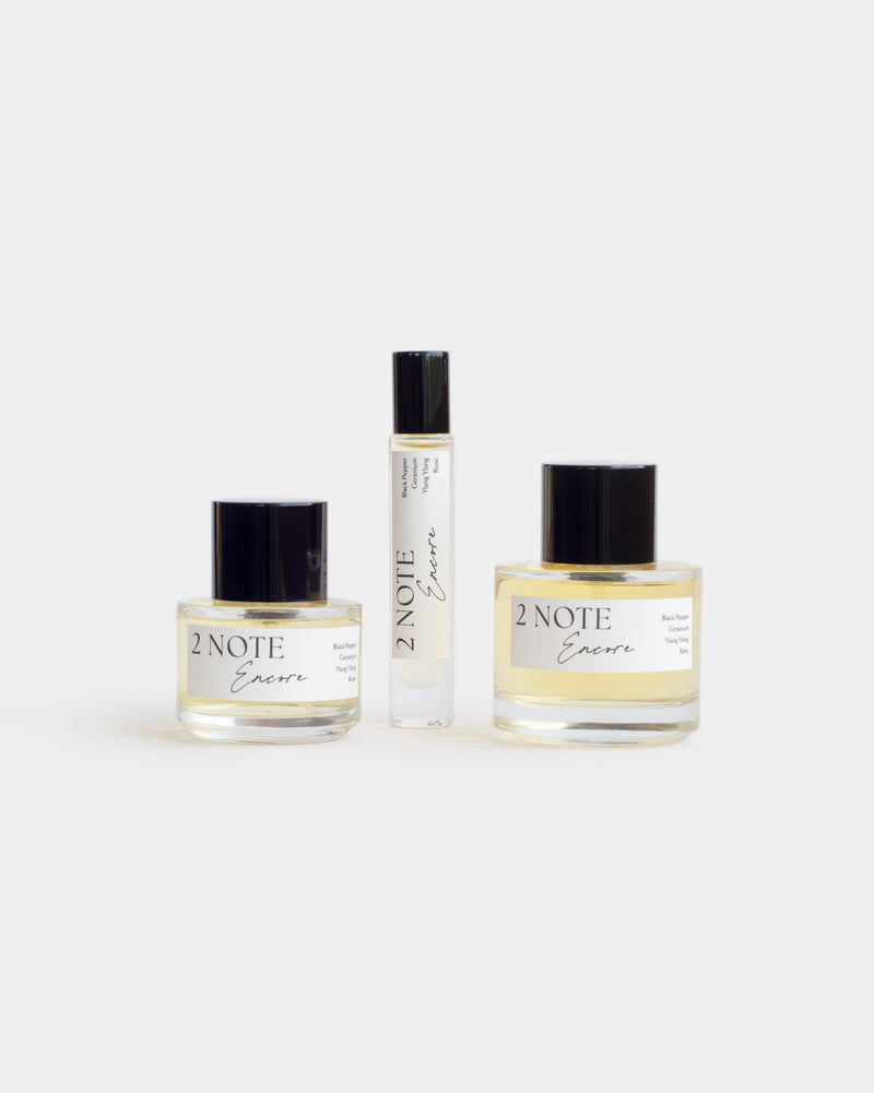 Encore botanical fragrance in three sizes — small and large spray bottles and a roller, pale straw oil through clear glass