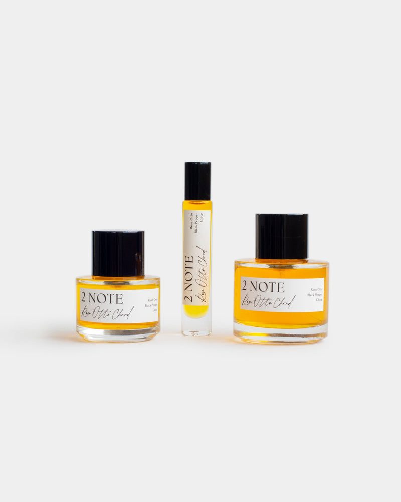 Rose Otto Chord botanical fragrance in three sizes — small and large spray bottles and a roller, golden yellow oil through clear glass
