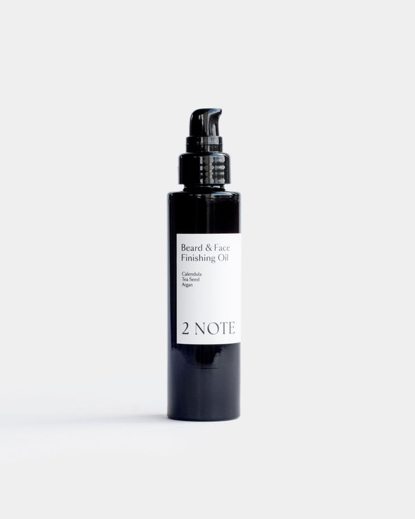 Beard and Face Finishing Oil in tall matte black pump bottle — botanical natural skincare with Calendula, Tea Seed, and Argan, front view on white