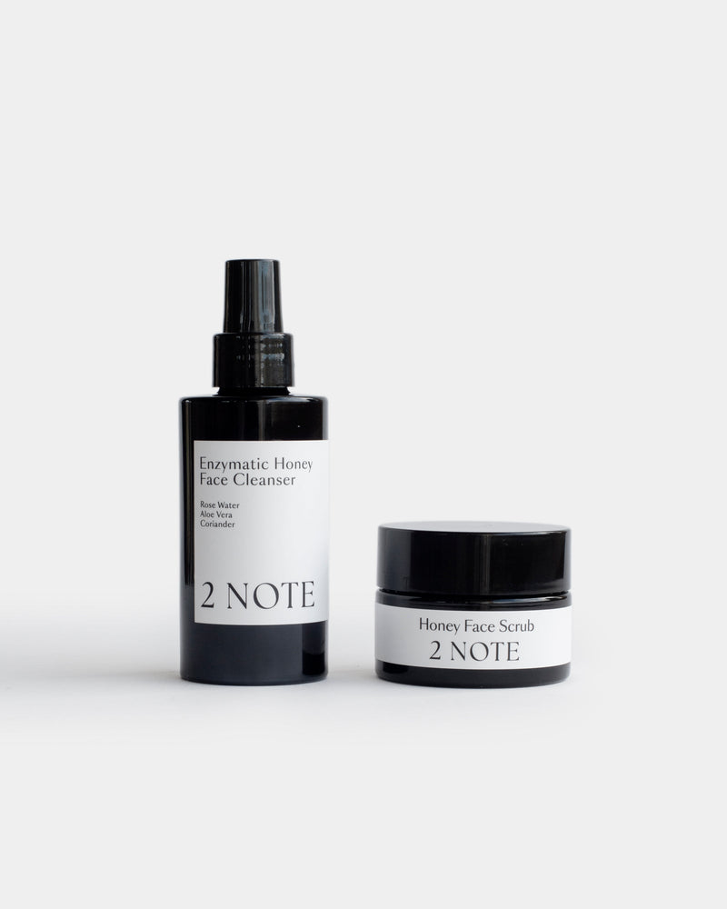 The Honey Set — Enzymatic Honey Face Cleanser matte black spray bottle and Honey Face Scrub matte black jar side by side on light gray, botanical skincare face cleansing duo
