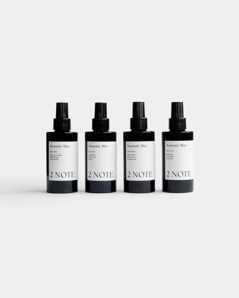Four Aromatic Mist matte black spray bottles side by side — all scent variants of this botanical fragrance room mist, light gray background