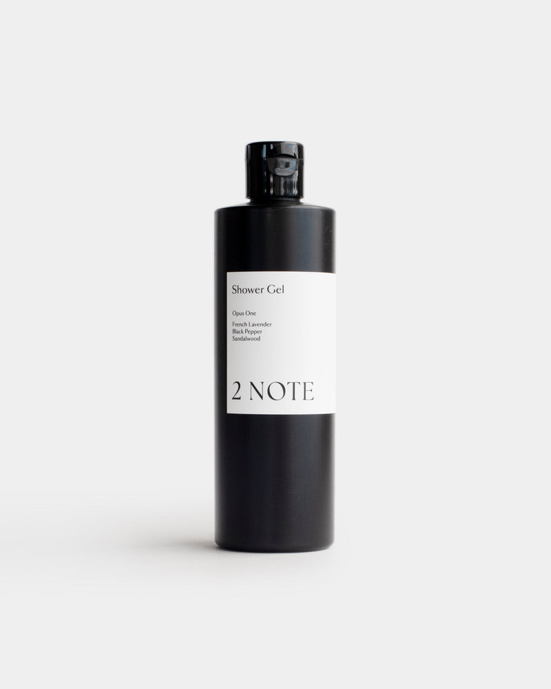 Shower Gel in tall matte black flip-top bottle — botanical skincare body wash with French Lavender, Black Pepper, and Sandalwood, front view on light gray
