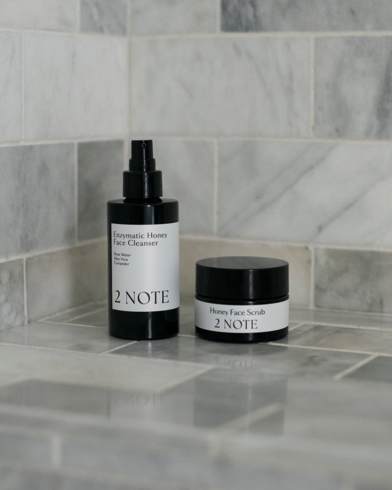 Honey Face Scrub and Enzymatic Honey Face Cleanser on marble tile surface — botanical natural skincare duo