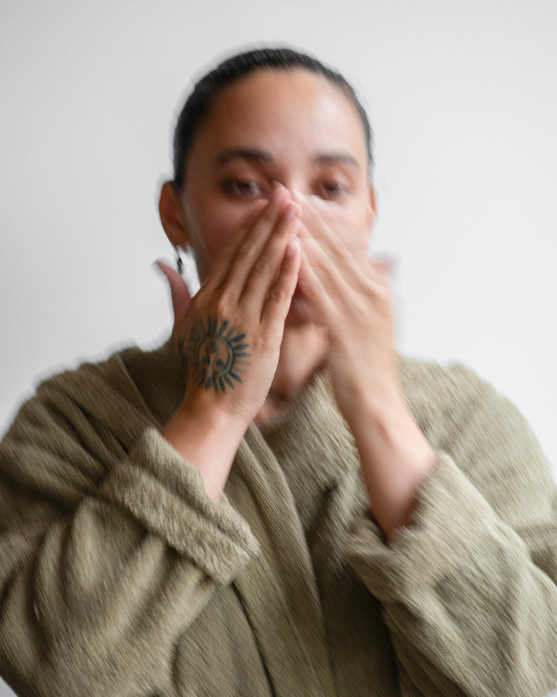 Queer nonbinary model with light olive complexion applying Honey Face Cleanser — natural botanical skincare application, close-up