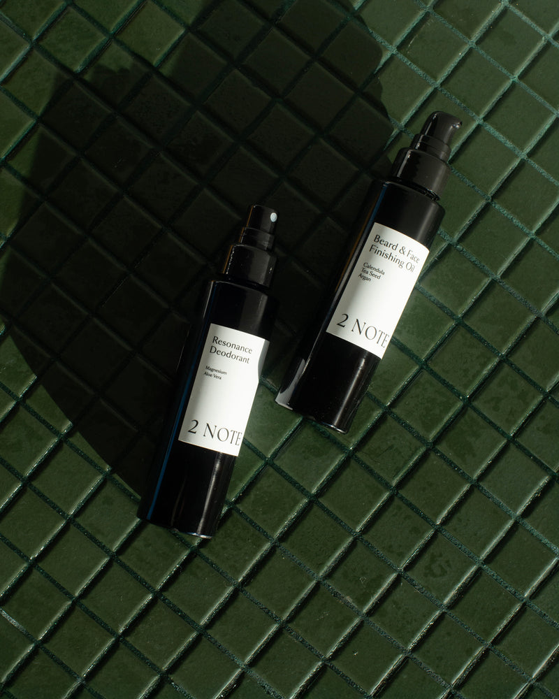 Queer nonbinary model with light olive complexion applying Beard and Face Finishing Oil — natural botanical skincare for beard and face