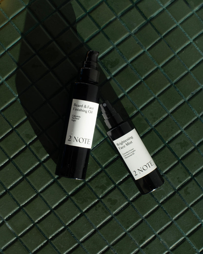 Queer nonbinary model with light olive complexion using Brightening Face Mist — natural botanical skincare application