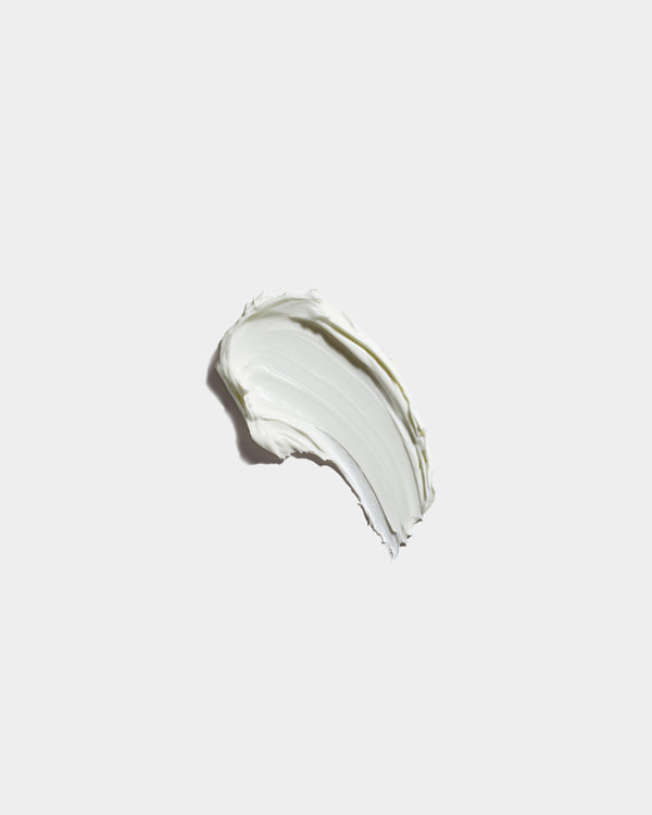 Hand Cream formula swatch — thick white botanical skincare cream smear on light gray surface