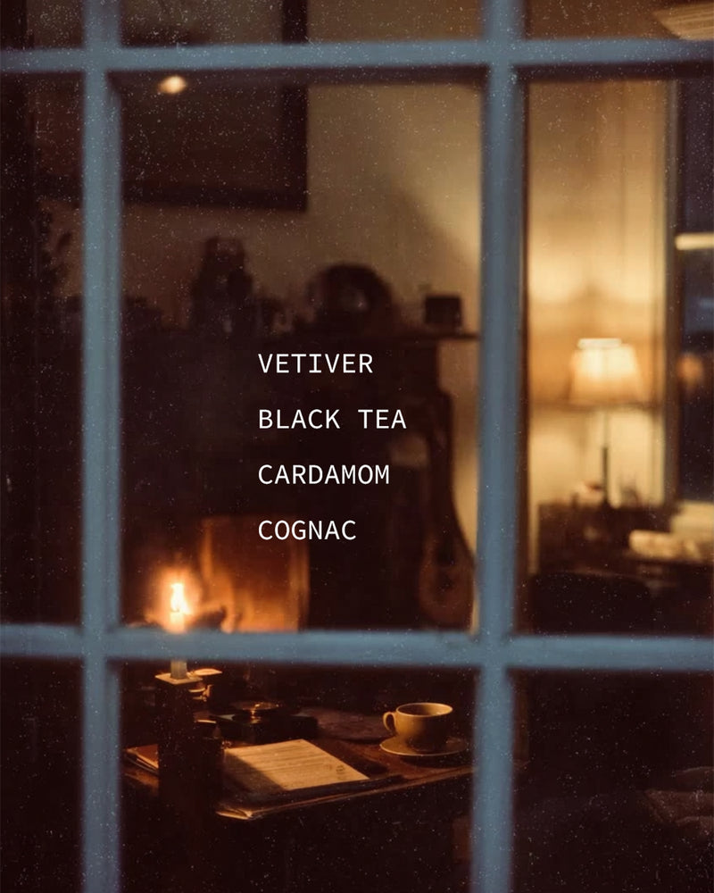 Cozy candlelit room viewed through a window at night — mood portrait for Nocturne botanical fragrance with Vetiver, Black Tea, Cardamom, and Cognac